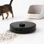 Robot aspirador recogiendo arena de gato junto al arenero